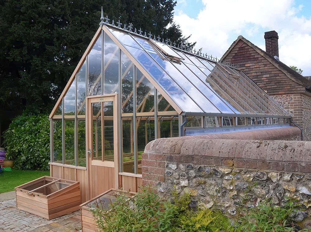 Frontl side view of a customized Alton Westminster Greenhouse installed against a wall