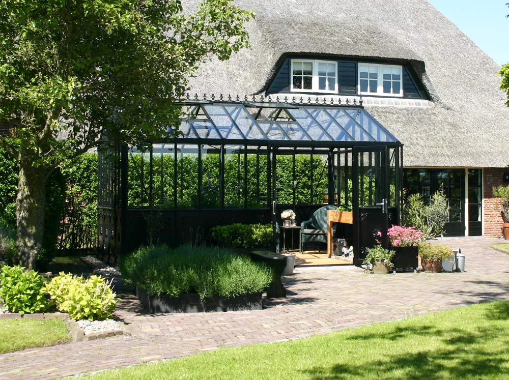Black Janssens Retro Victorian Greenhouse set up behind a house in the backyard