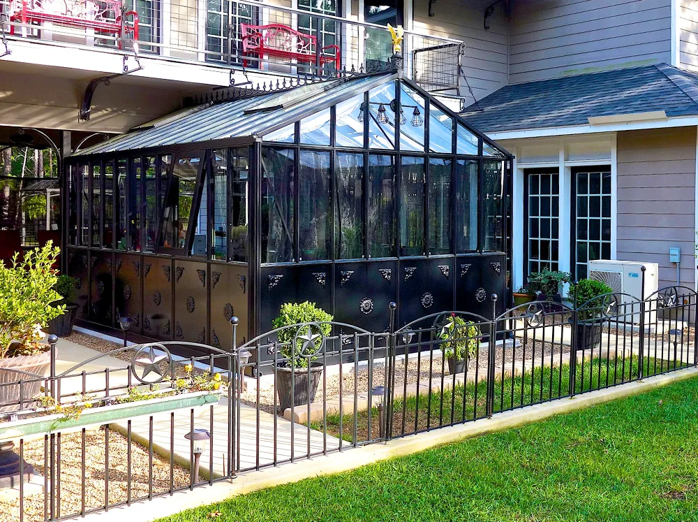 Black Janssens Retro Victorian Greenhouse set up against a house