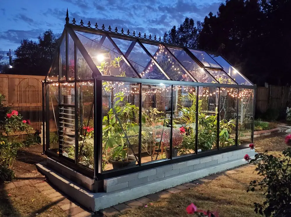Exterior shot of a glass Janssens glass greenhouse on a cinder block foundation
