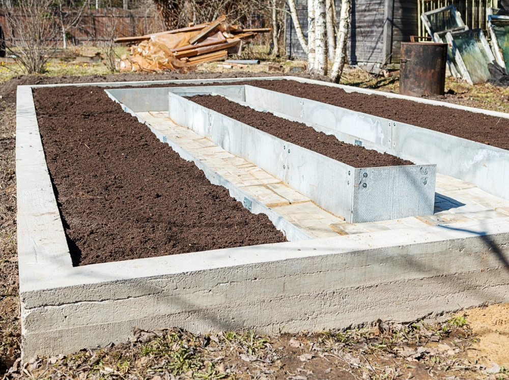 Poured concrete greenhouse foundation with raised beds built in.