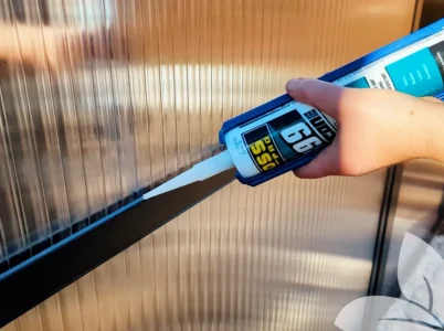 Person caulking a greenhouse with BOSS silicone sealant in a caulk gun