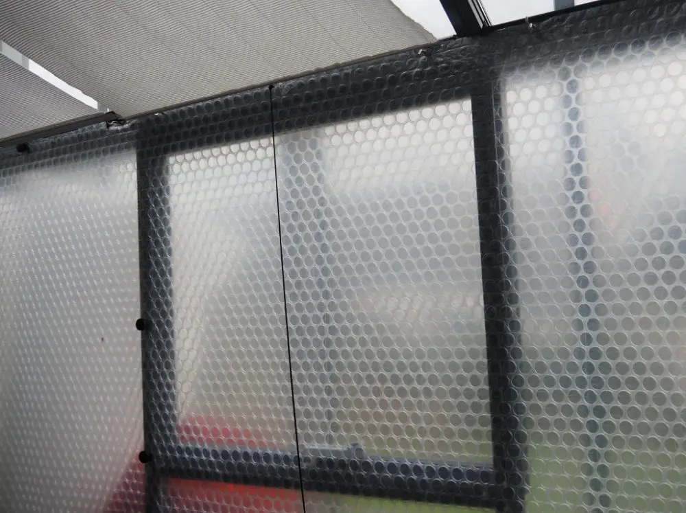 Insulating bubble wrap on the inside of a greenhouse wall.