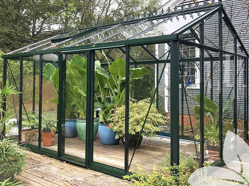 Glass greenhouse on a deck with large potted plants inside