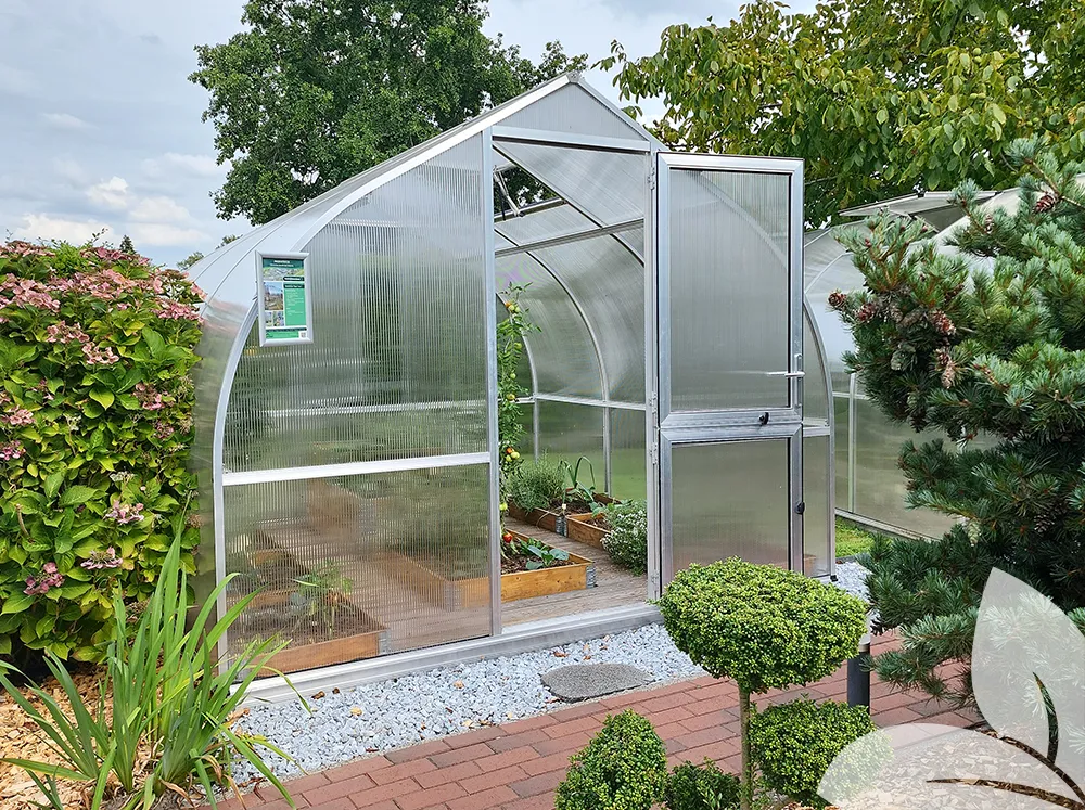 Front of a polycarbonate greenhouse in a garden with the door open