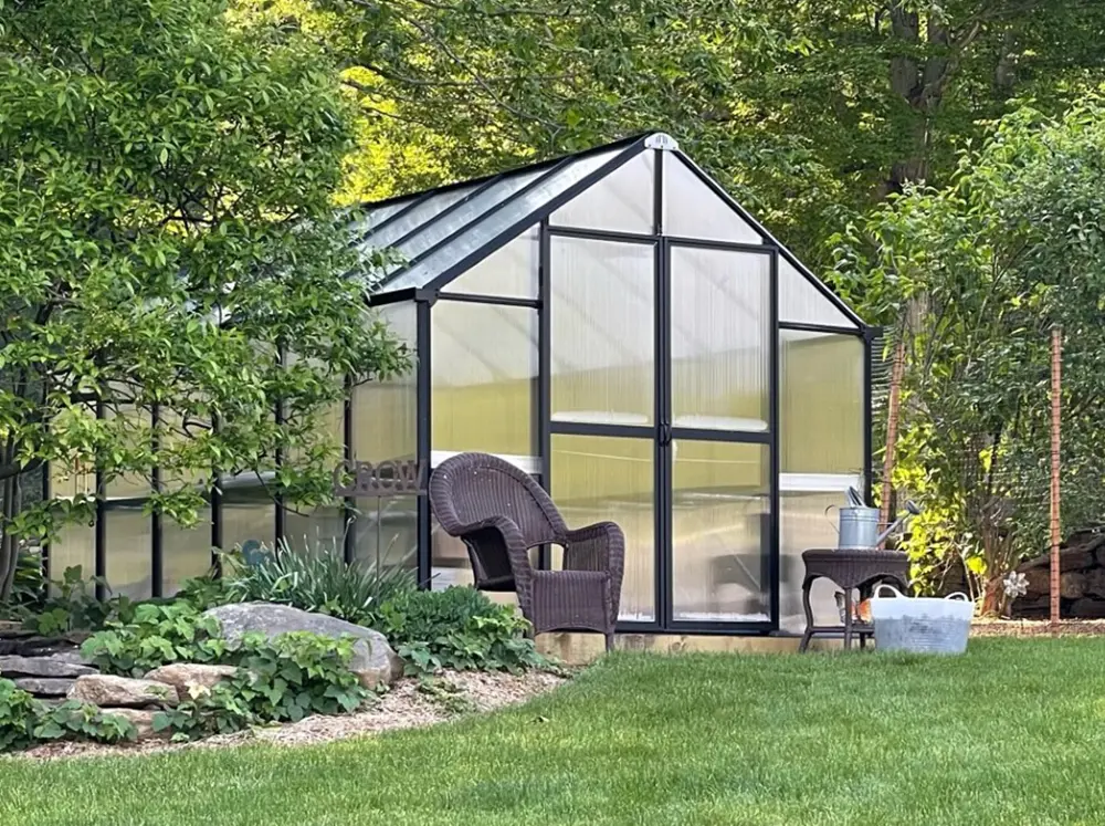 MONT greenhouse in a green backyard with a chair in front