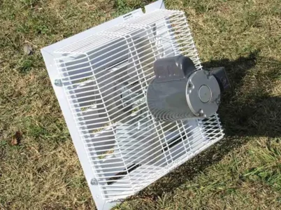 Interior side of the RSI Greenhouse Exhaust Fan System sitting on a lawn