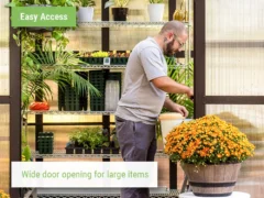 Wide door opening of the Vego Pacific 8.5 Greenhouse with a large planter in front and a person working inside the greenhouse