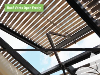 Interior view of a greenhouse with the Wood Slatted Greenhouse Shades installed on the roof, showing the roof vent opens freely