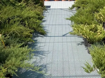 Grey RSI Interlocking Flooring Tiles installed as a path in a backyard with shrubs lining the path