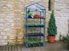 4-tier Genesis Portable Rolling Mini Greenhouse with clear cover on a patio