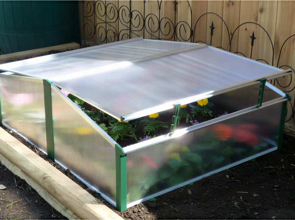 Juwel Easy-Fix Double Cold Frame on a garden bed with flowers inside