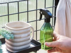 Person hanging a spray bottle on the Vego Greenhouse Hanging Grid System