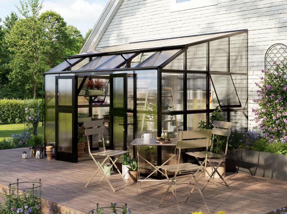 Vego Grand Lean-To Greenhouse installed against a house wall with a bistro table set in front